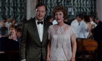 Movie still from “Bon Voyage!” (1962), directed by James Neilson – A man and a woman standing next to each other; Medium shot, Low angle