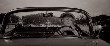 A woman sitting in the driver's seat of an old car