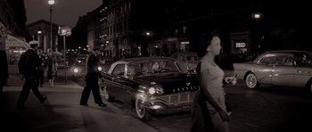 Movie still from “Bonjour Tristesse” (1958), directed by Otto Preminger – An old black and white photo of a car on the street; Wide shot, High angle