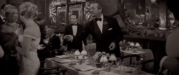 Movie still from “Bonjour Tristesse” (1958), directed by Otto Preminger – A man in a tuxedo standing in front of a dinner table; Medium shot, Low angle