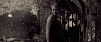 A woman in a black dress standing in front of a stone wall