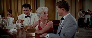 Movie still from “Bonjour Tristesse” (1958), directed by Otto Preminger – An older woman sitting at a table with two men; Medium shot, Over the shoulder angle