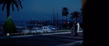 Movie still from “Bonjour Tristesse” (1958), directed by Otto Preminger – Two people walking down the street at night near a parking lot; Extreme Wide shot, Low angle