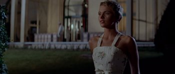 Movie still from “Bonjour Tristesse” (1958), directed by Otto Preminger – A woman in a white dress standing in front of a building; Medium shot, Low angle