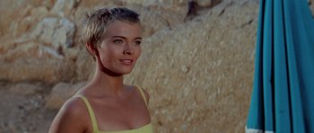 Movie still from “Bonjour Tristesse” (1958), directed by Otto Preminger – A woman in a yellow top standing in front of a rock wall; Close Up shot, Low angle