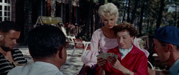 Movie still from “Bonjour Tristesse” (1958), directed by Otto Preminger – Two women and a man playing cards on a sidewalk; Medium shot, Over the shoulder angle