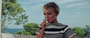 A woman in a striped shirt smoking a cigarette