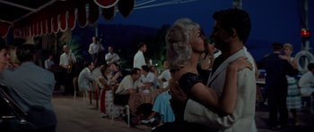 Movie still from “Bonjour Tristesse” (1958), directed by Otto Preminger – A man and a woman kissing in front of a crowd; Medium shot, Low angle