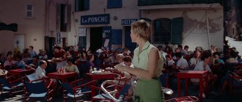 Movie still from “Bonjour Tristesse” (1958), directed by Otto Preminger – A woman standing in front of a group of people in a restaurant; Wide shot, High angle