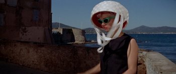 Movie still from “Bonjour Tristesse” (1958), directed by Otto Preminger – A person wearing a hat and sunglasses near the ocean; Medium shot, Low angle