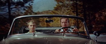 Movie still from “Bonjour Tristesse” (1958), directed by Otto Preminger – A man and a boy driving a car in the road; Medium shot, Low angle