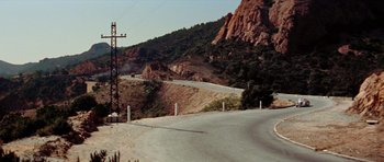 Movie still from “Bonjour Tristesse” (1958), directed by Otto Preminger – A view of a mountain road with power lines on the side of the road; Extreme Wide shot, High angle