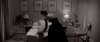 Movie still from “Bonjour Tristesse” (1958), directed by Otto Preminger – A woman in a black dress is petting a white dog; Medium shot, High angle