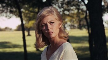 Movie still from “Bonnie and Clyde” (1967), directed by Arthur Penn – A woman in a white shirt is standing in a park; Close Up shot, Low angle