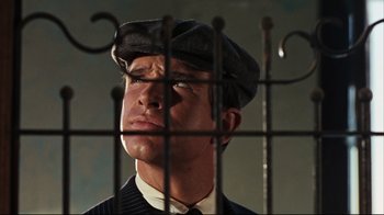 Movie still from “Bonnie and Clyde” (1967), directed by Arthur Penn – A man wearing a hat looking through a fence; Close Up shot, Low angle