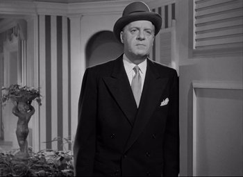Movie still from “Born Yesterday” (1950), directed by George Cukor – An old photo of a man in a suit and hat; Medium shot, Low angle