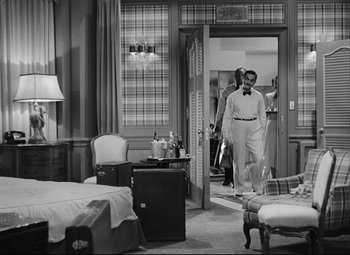 Movie still from “Born Yesterday” (1950), directed by George Cukor – A black and white photo of a man standing in a room; Wide shot, High angle