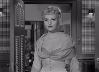 Movie still from “Born Yesterday” (1950), directed by George Cukor – A black - and - white photo of a woman in a dress; Medium shot, Low angle