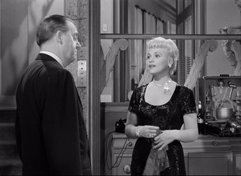 Movie still from “Born Yesterday” (1950), directed by George Cukor – An old photo of a man and a woman talking; Medium shot, Over the shoulder angle