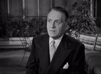 Movie still from “Born Yesterday” (1950), directed by George Cukor – An old black and white photo of a man in a suit and tie; Close Up shot, Low angle