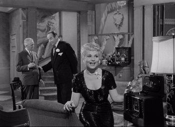 Movie still from “Born Yesterday” (1950), directed by George Cukor – An older woman sitting on top of a couch in a living room; Medium shot, High angle