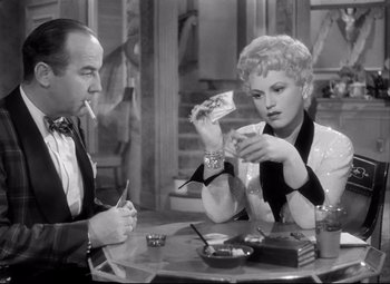 Movie still from “Born Yesterday” (1950), directed by George Cukor – A man and a woman sitting at a table; Medium shot, High angle