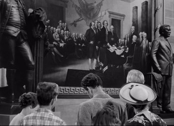 Movie still from “Born Yesterday” (1950), directed by George Cukor – A group of people standing in front of a painting of the declaration of independence; Wide shot, High angle