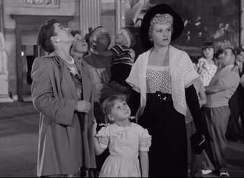 Movie still from “Born Yesterday” (1950), directed by George Cukor – A group of women and a girl standing next to each other; Medium shot, Low angle