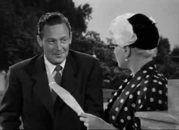 Movie still from “Born Yesterday” (1950), directed by George Cukor – An older man wearing a suit talking to an older woman wearing a hat; Medium shot, Over the shoulder angle