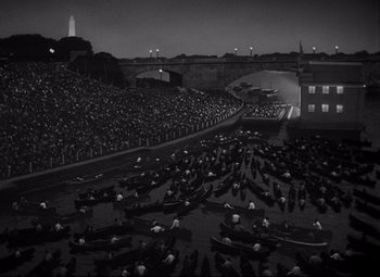 Movie still from “Born Yesterday” (1950), directed by George Cukor – A large group of people in boats in a stadium; Extreme Wide shot, High angle