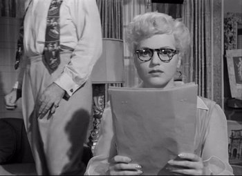 Movie still from “Born Yesterday” (1950), directed by George Cukor – An old photo of a woman holding a book; Medium shot, Low angle