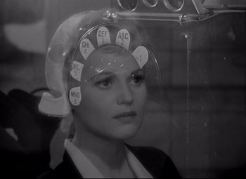 Movie still from “Born Yesterday” (1950), directed by George Cukor – A black and white photo of a woman with a hair dryer on her head; Close Up shot, Over the shoulder angle
