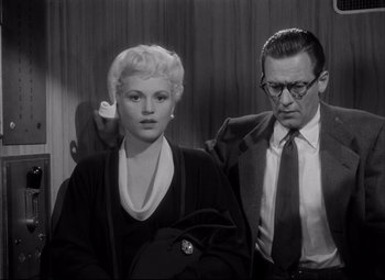 Movie still from “Born Yesterday” (1950), directed by George Cukor – A man and a woman standing next to each other; Medium shot, Low angle