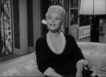 Movie still from “Born Yesterday” (1950), directed by George Cukor – A woman sitting on a couch in a living room; Medium shot, Low angle