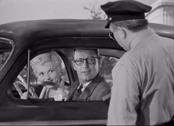 Movie still from “Born Yesterday” (1950), directed by George Cukor – An old photo of a man and a woman in a car; Medium shot, Over the shoulder angle
