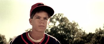 Movie still from “Born on the Fourth of July” (1989), directed by Oliver Stone – A young baseball player is looking at the camera; Close Up shot, Low angle