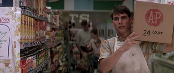 Movie still from “Born on the Fourth of July” (1989), directed by Oliver Stone – A young man in a grocery store holding a knife; Medium shot, Over the shoulder angle