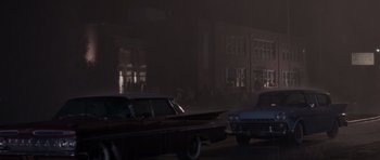Movie still from “Born on the Fourth of July” (1989), directed by Oliver Stone – A couple of cars parked on the side of a road; Extreme Wide shot, Low angle