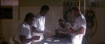 Movie still from “Born on the Fourth of July” (1989), directed by Oliver Stone – A group of men standing around a table in a kitchen; Medium shot, High angle