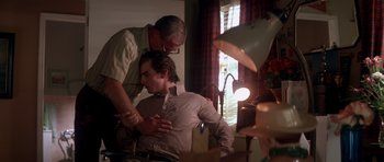 Movie still from “Born on the Fourth of July” (1989), directed by Oliver Stone – An older man helping a younger man with his tie; Medium shot, Over the shoulder angle