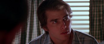 Movie still from “Born on the Fourth of July” (1989), directed by Oliver Stone – A young man looking into the distance while sitting in front of a window; Close Up shot, Over the shoulder angle
