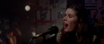 Movie still from “Born on the Fourth of July” (1989), directed by Oliver Stone – A woman singing into a microphone in front of a crowd; Close Up shot, Low angle