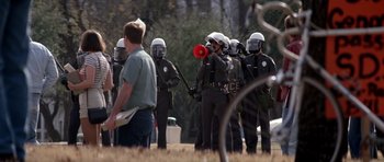 Movie still from “Born on the Fourth of July” (1989), directed by Oliver Stone – A group of police officers standing in a field; Wide shot, Over the shoulder angle