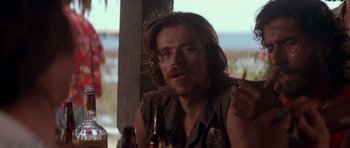 Movie still from “Born on the Fourth of July” (1989), directed by Oliver Stone – A man sitting at a table in front of a bottle of beer; Close Up shot, Over the shoulder angle