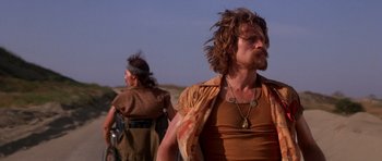 Movie still from “Born on the Fourth of July” (1989), directed by Oliver Stone – A man with long hair is standing next to another man with long hair; Medium shot, Low angle