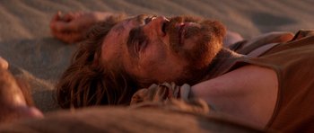Movie still from “Born on the Fourth of July” (1989), directed by Oliver Stone – A man with long hair and a beard laying on the ground; Close Up shot, High angle