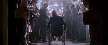 Movie still from “Born on the Fourth of July” (1989), directed by Oliver Stone – A woman in a wheelchair in a crowd of people; Wide shot, High angle