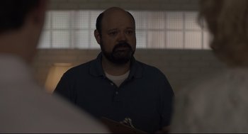 Movie still from “Boy Erased” (2018), directed by Joel Edgerton – A man with a beard is standing in a dark room; Close Up shot, Over the shoulder angle