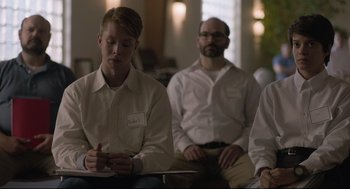 Movie still from “Boy Erased” (2018), directed by Joel Edgerton – A group of people sitting in a room; Medium shot, Over the shoulder angle