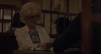 Movie still from “Boy Erased” (2018), directed by Joel Edgerton – An older woman sitting at a table looking at something on her phone; Medium shot, Over the shoulder angle
